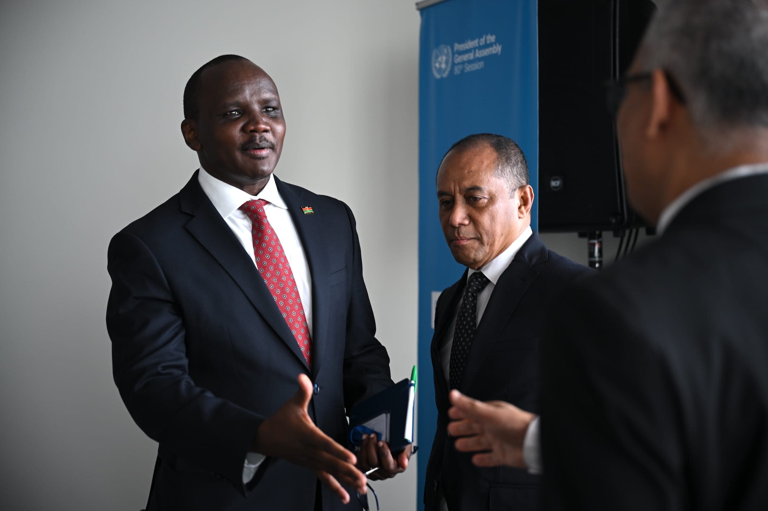 Two suited delegates speak during a meeting hosted by the President of the General Assembly.