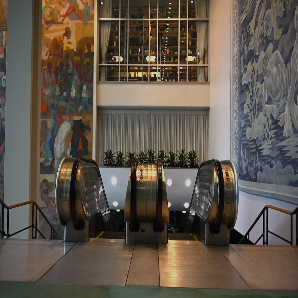 Escalators descend between murals inside United Nations Headquarters.