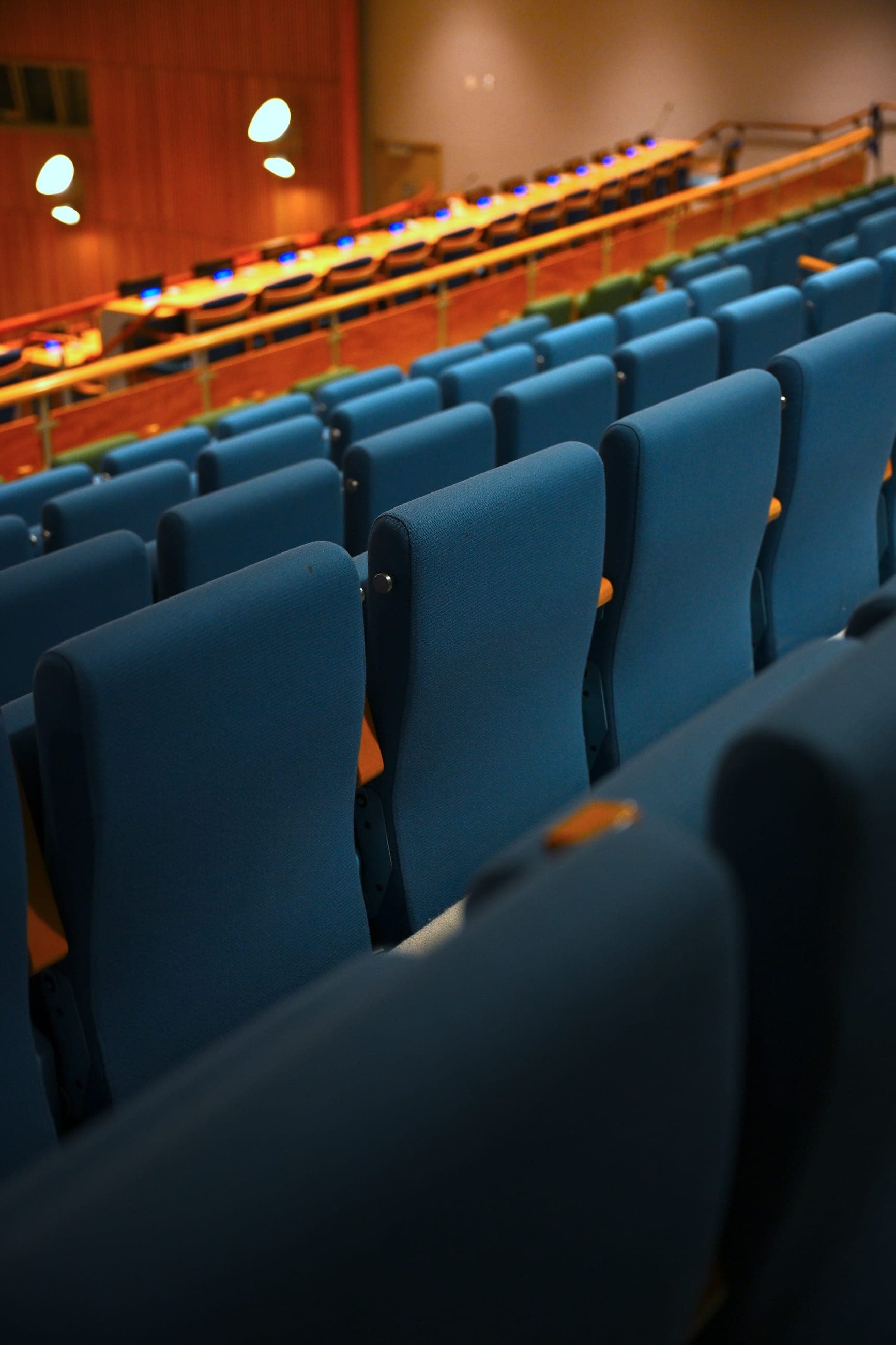 Rows of empty blue seats in a United Nations conference room.