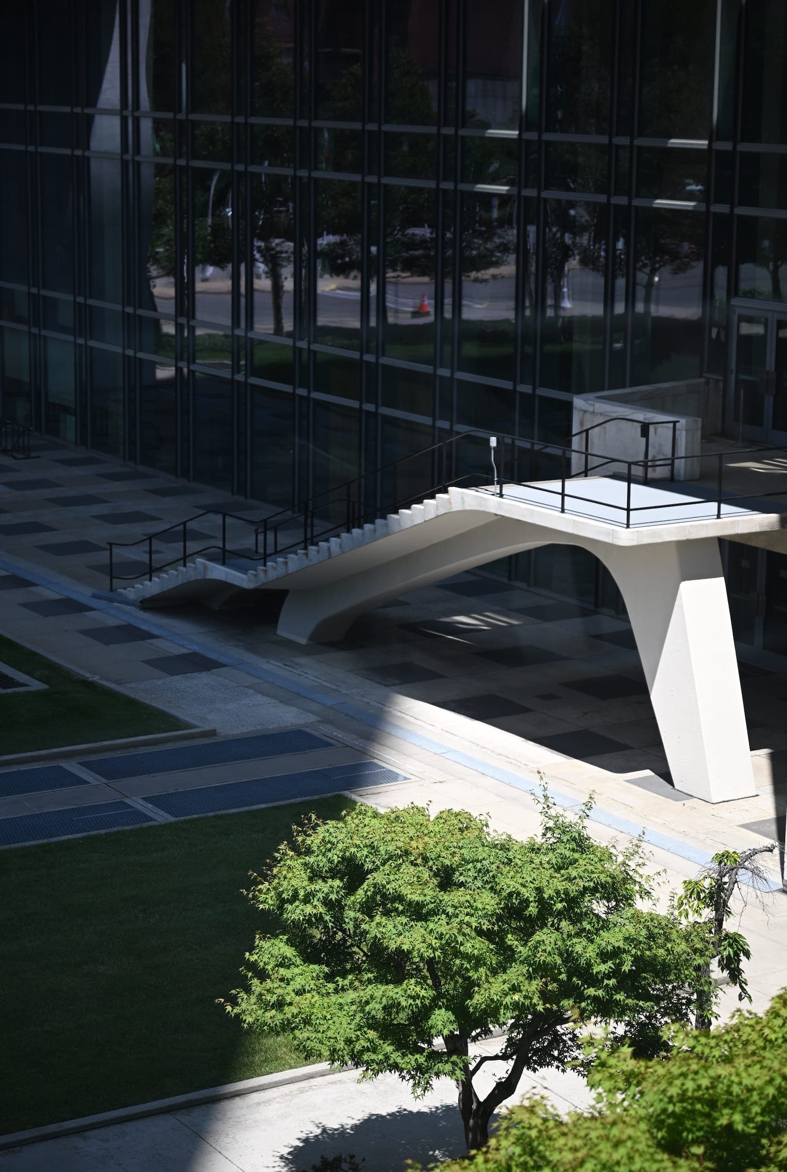 A raised walkway crosses a courtyard beside the glass facade of the United Nations Secretariat building.