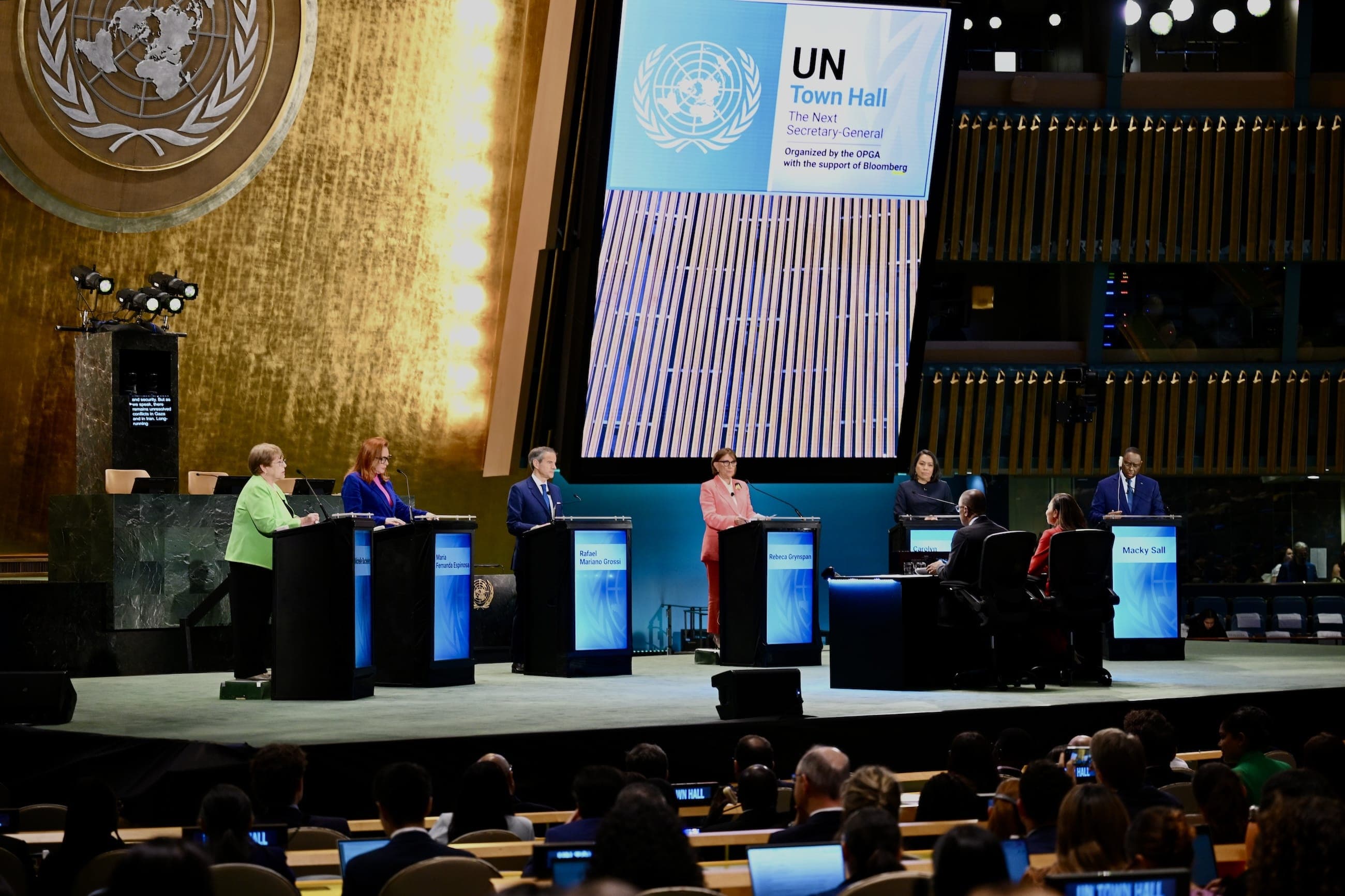 Secretary-General candidates stand at lecterns during a United Nations town hall in the General Assembly Hall.
