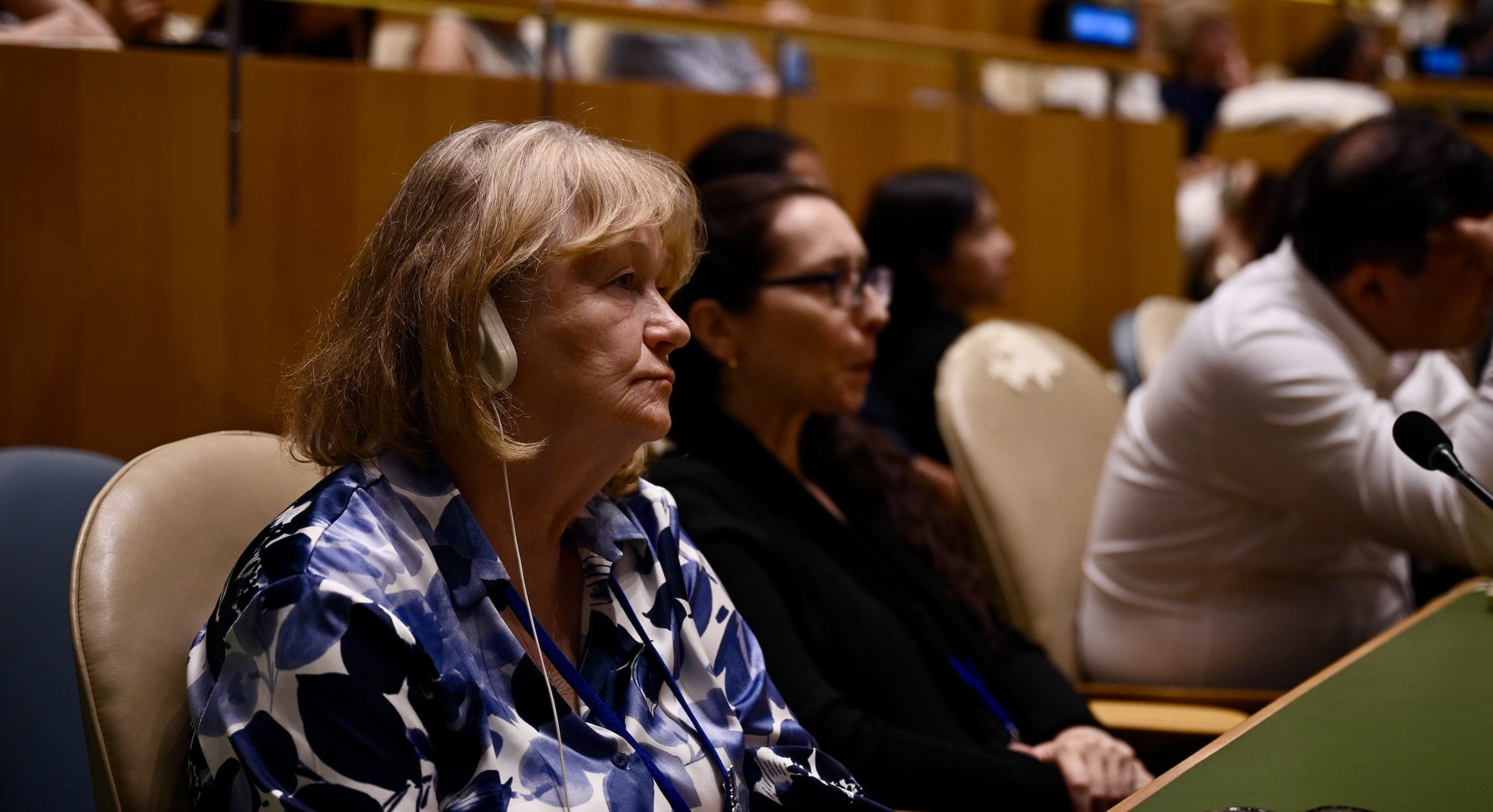 A woman wearing interpretation headphones listens from her seat in the General Assembly Hall.