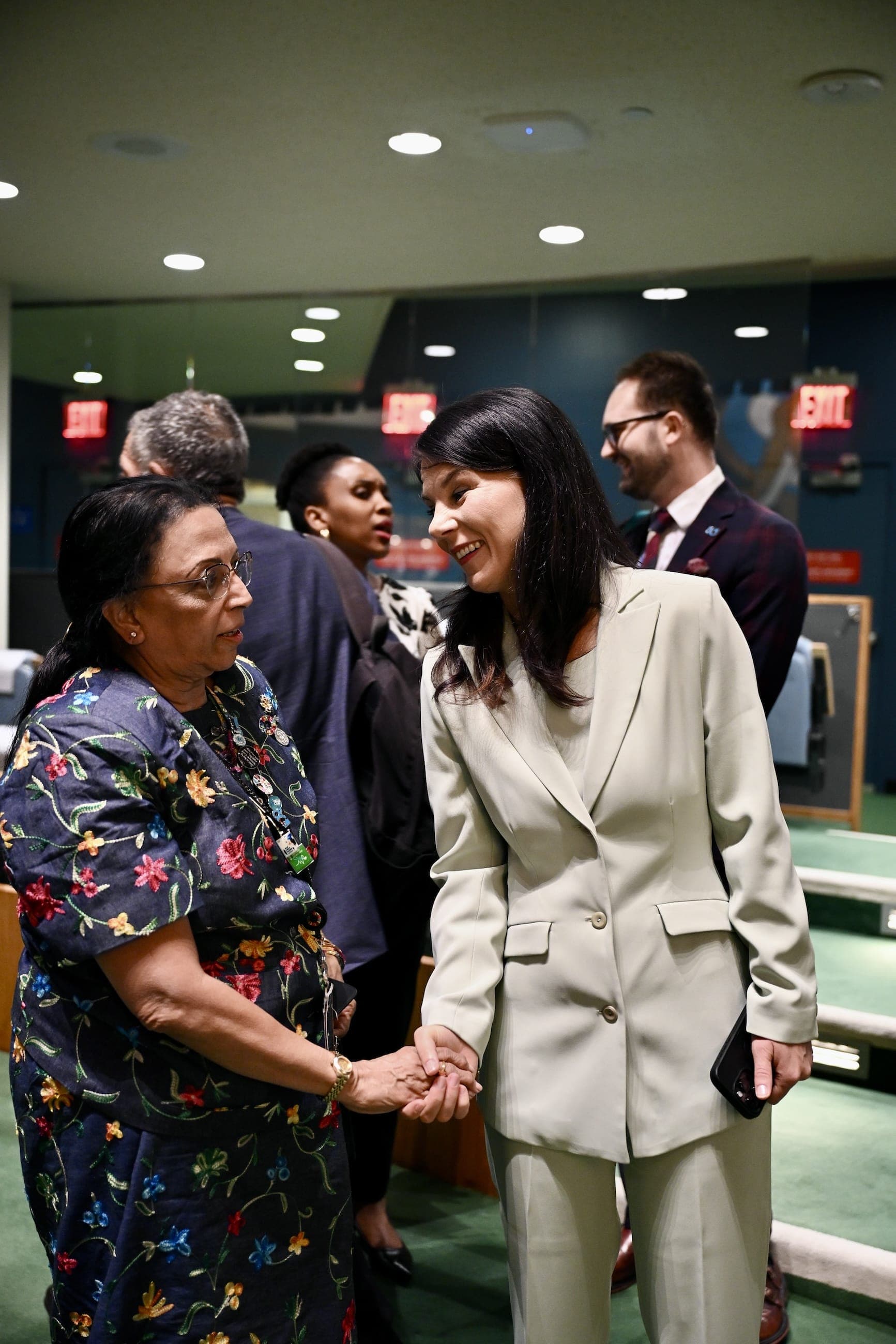 Two women shake hands during a reception in the General Assembly Hall.