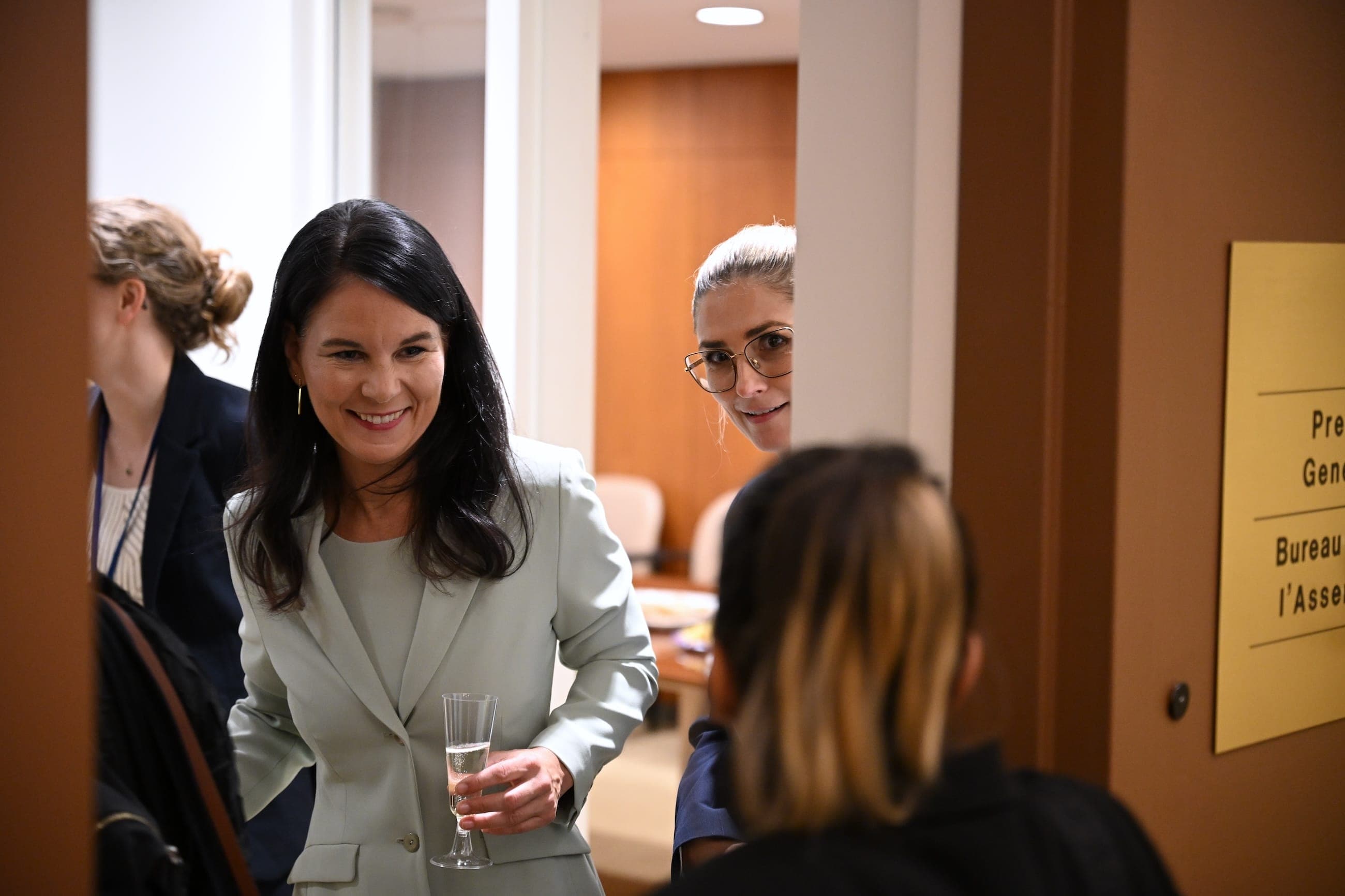 A woman in a light suit greets guests outside the President of the General Assembly’s office.