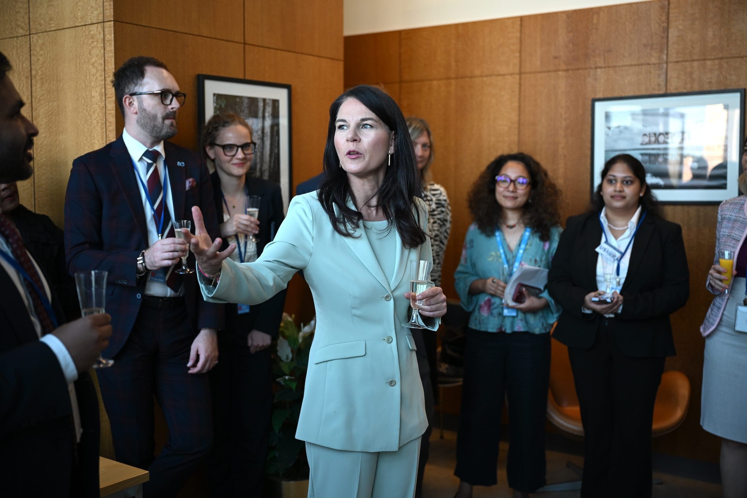 A woman in a light suit speaks to guests during a reception.