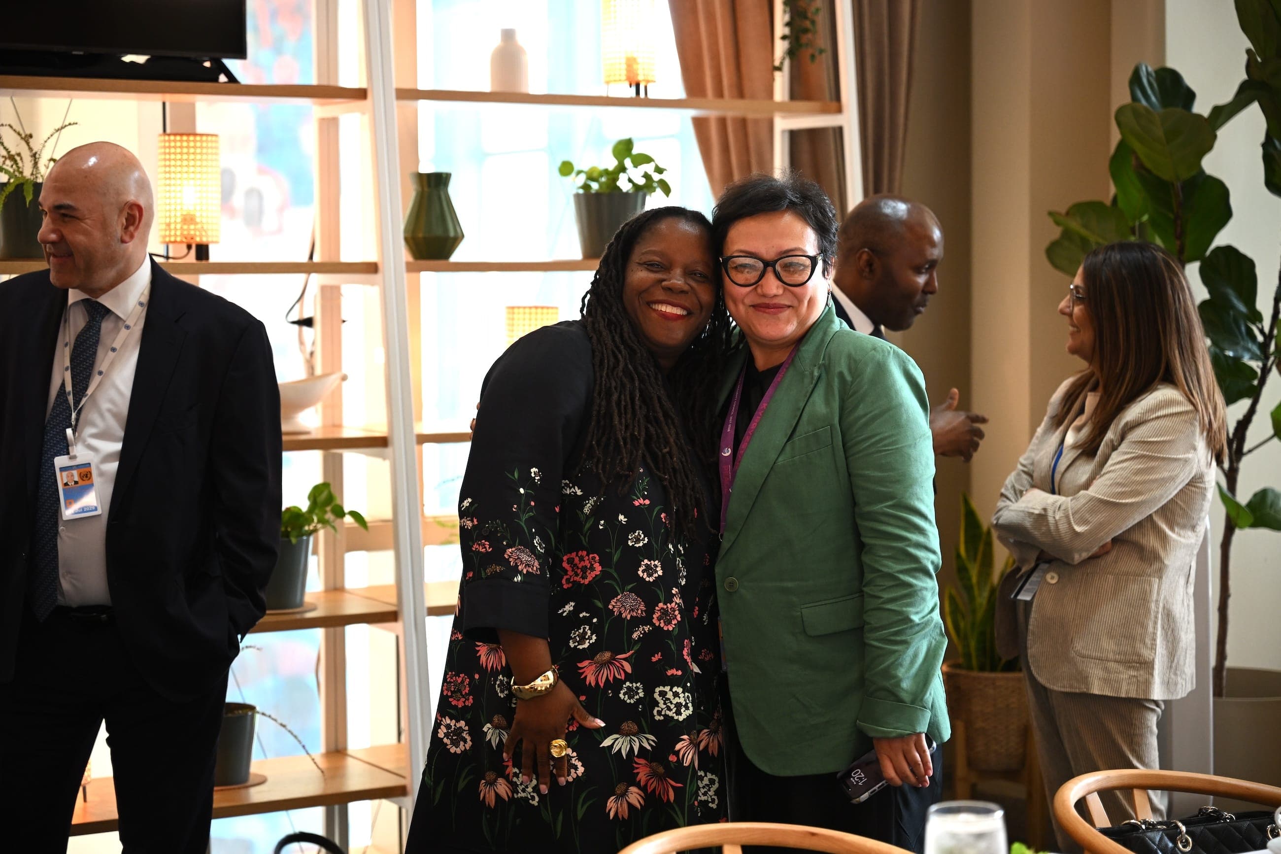 Two women embrace and smile during a reception.