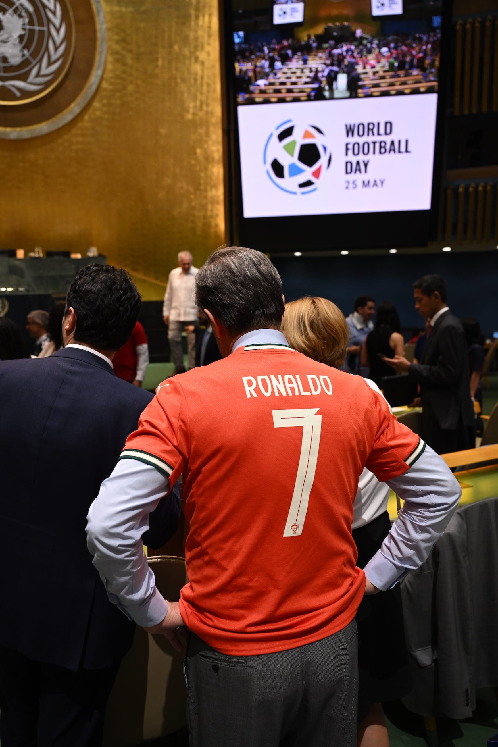 An attendee in a Ronaldo number seven shirt stands beneath a World Football Day display in the General Assembly Hall.