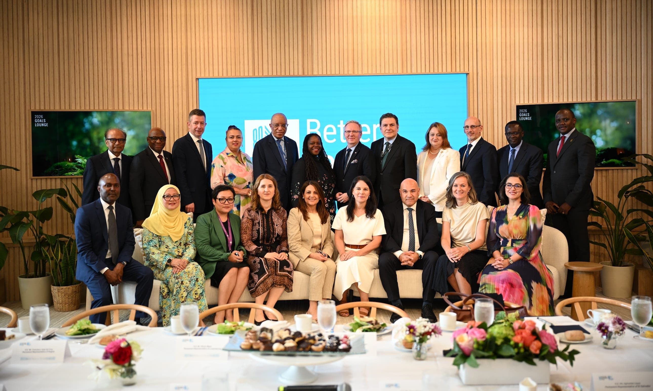 A large group of participants pose together in the United Nations Goals Lounge.