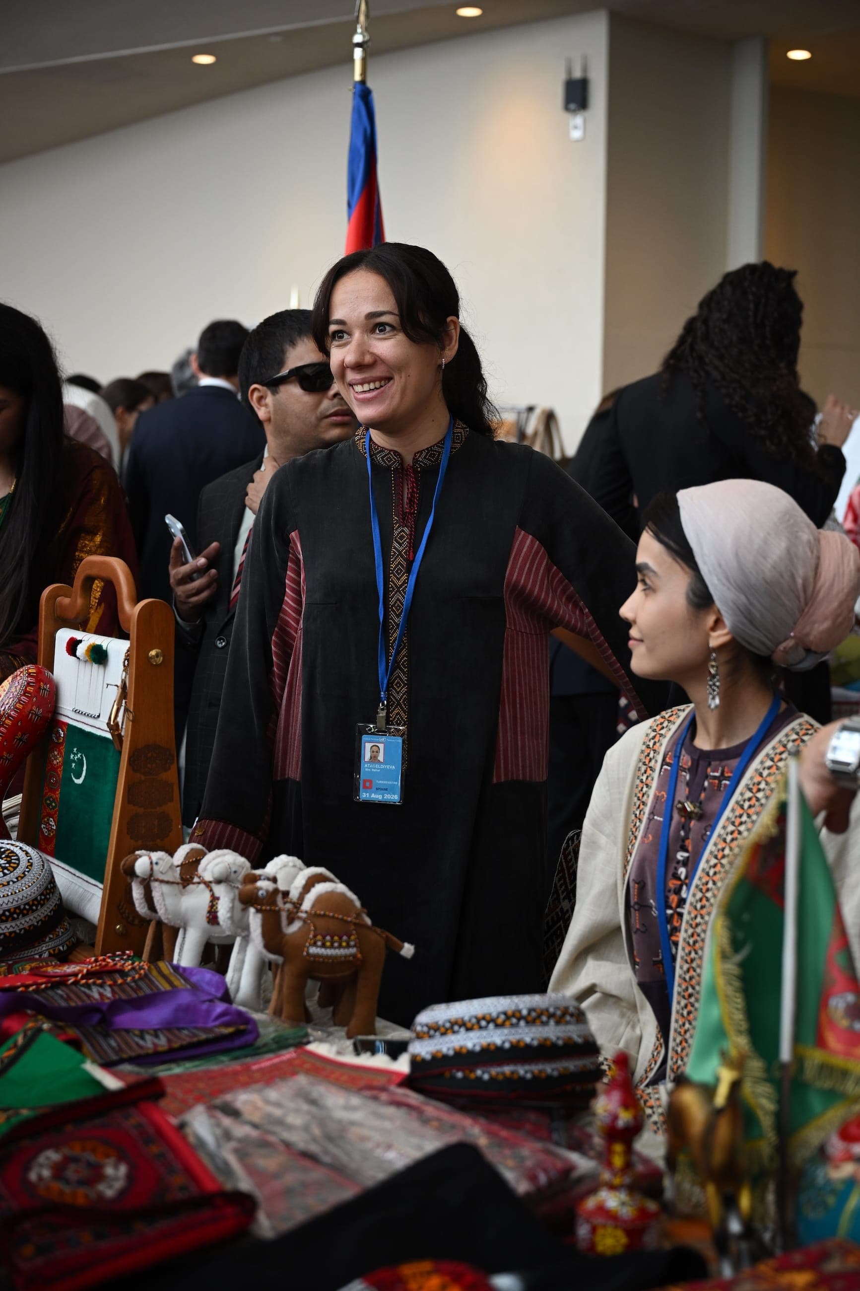 A woman and a girl stand behind a display of traditional crafts at a cultural event.