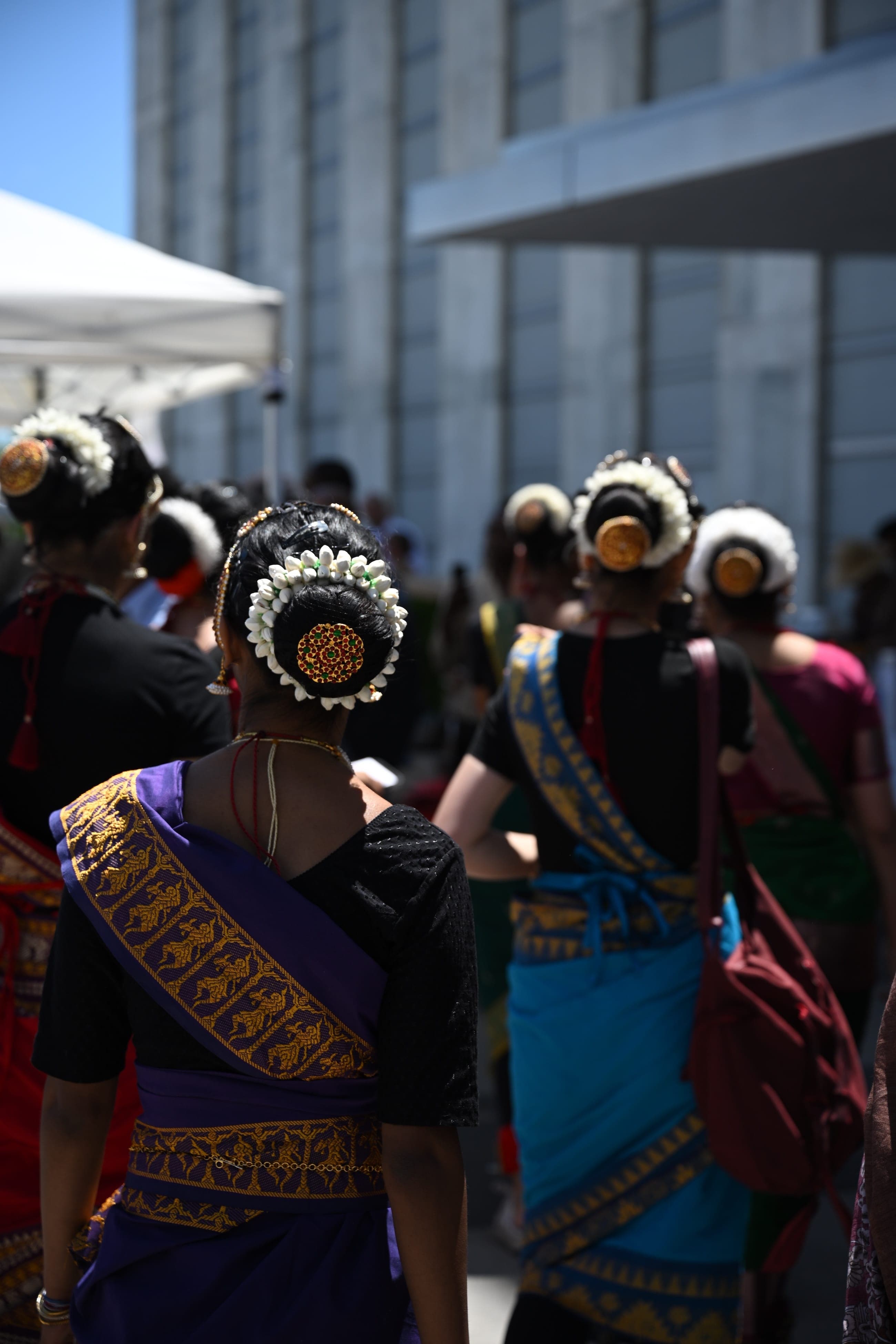 Women in traditional dress walk together at an outdoor cultural event.