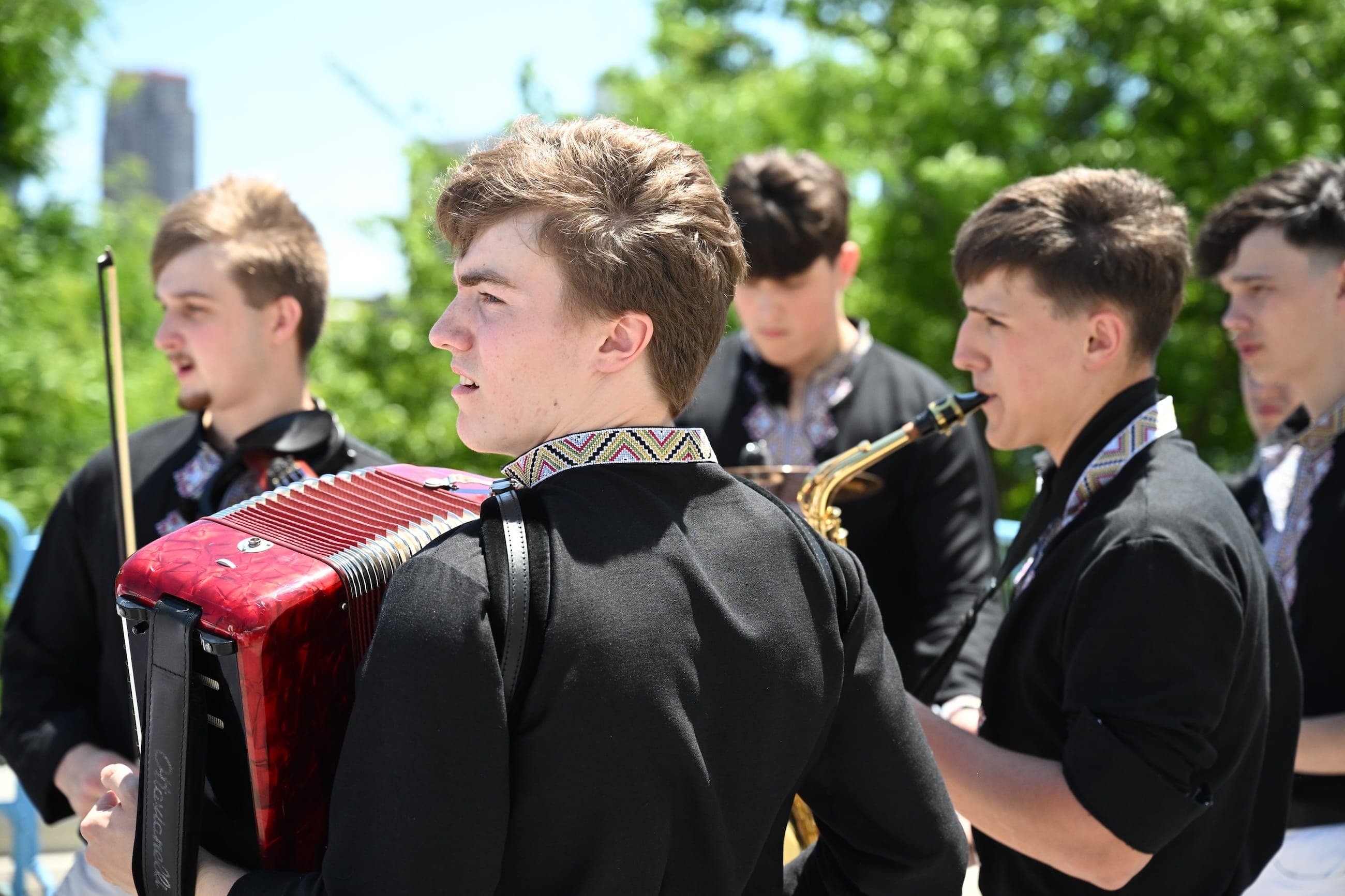 An accordion player performs with a band at an outdoor cultural event.