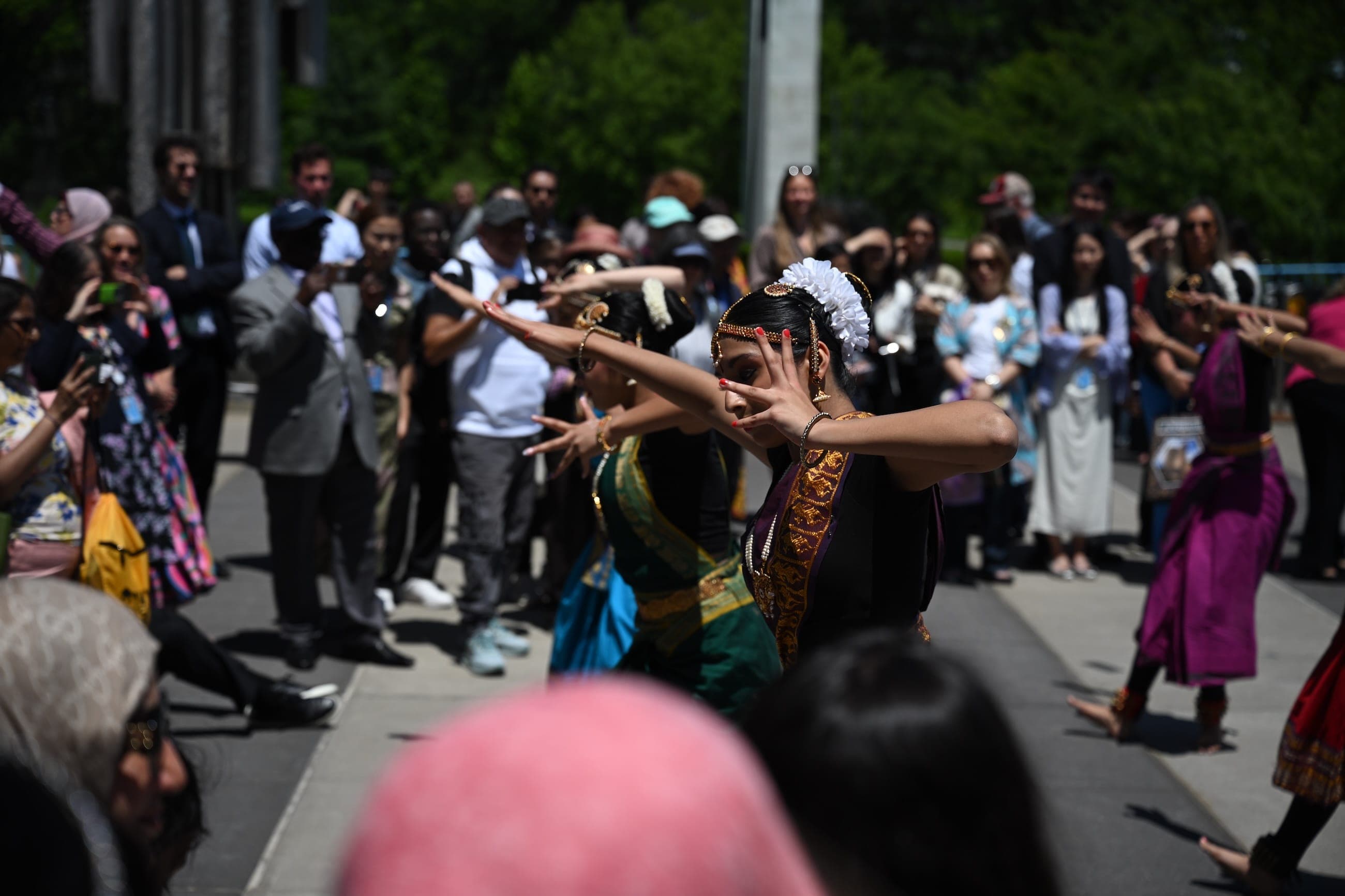 Dancers in traditional dress perform for a crowd at an outdoor cultural event.