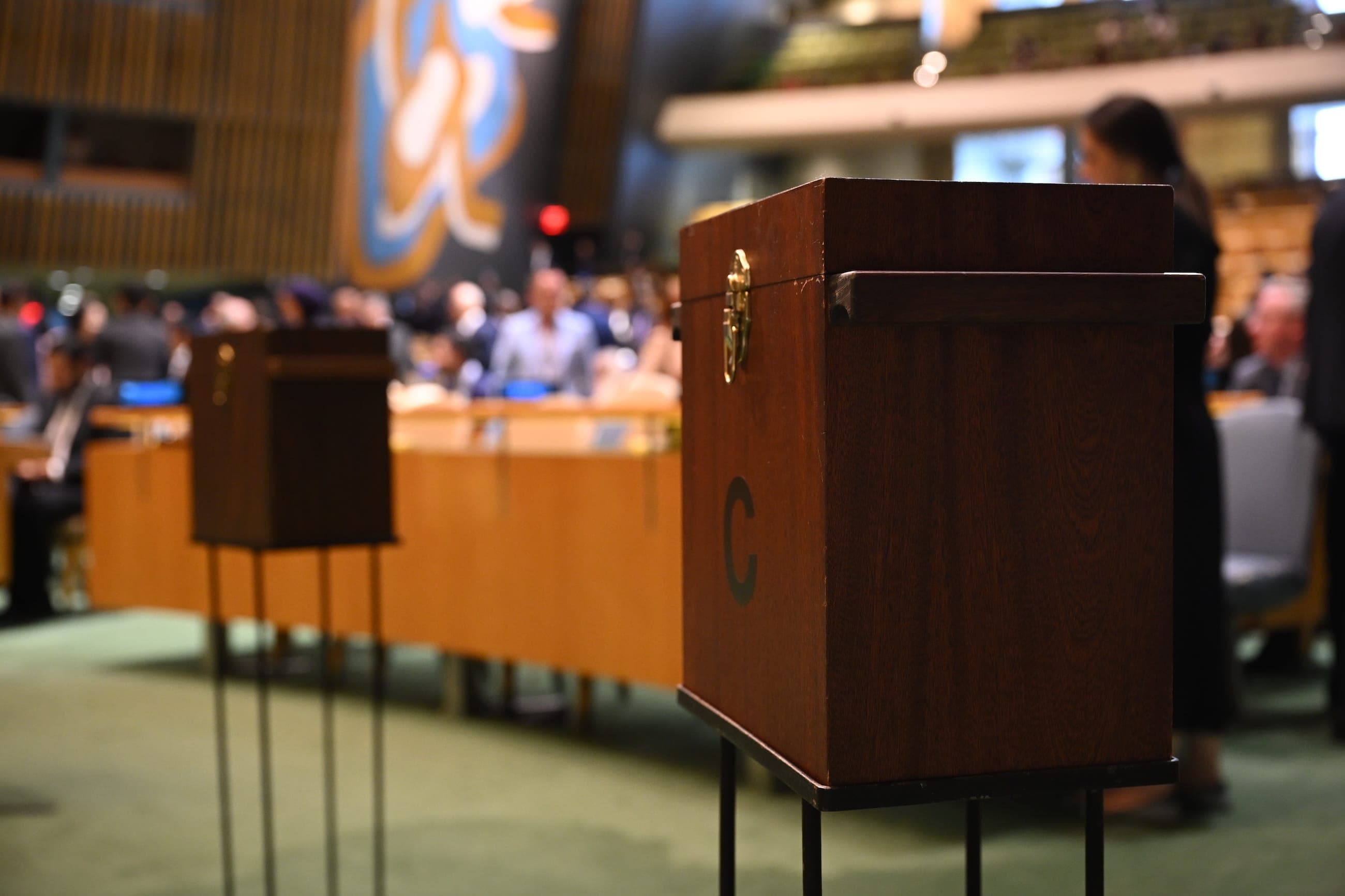Wooden ballot boxes stand among delegates in the General Assembly Hall.