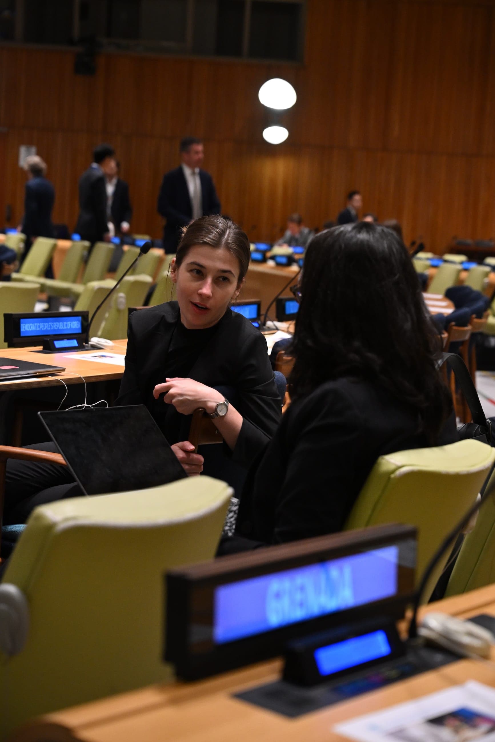 Two women confer at the Peru desk in a United Nations meeting room.