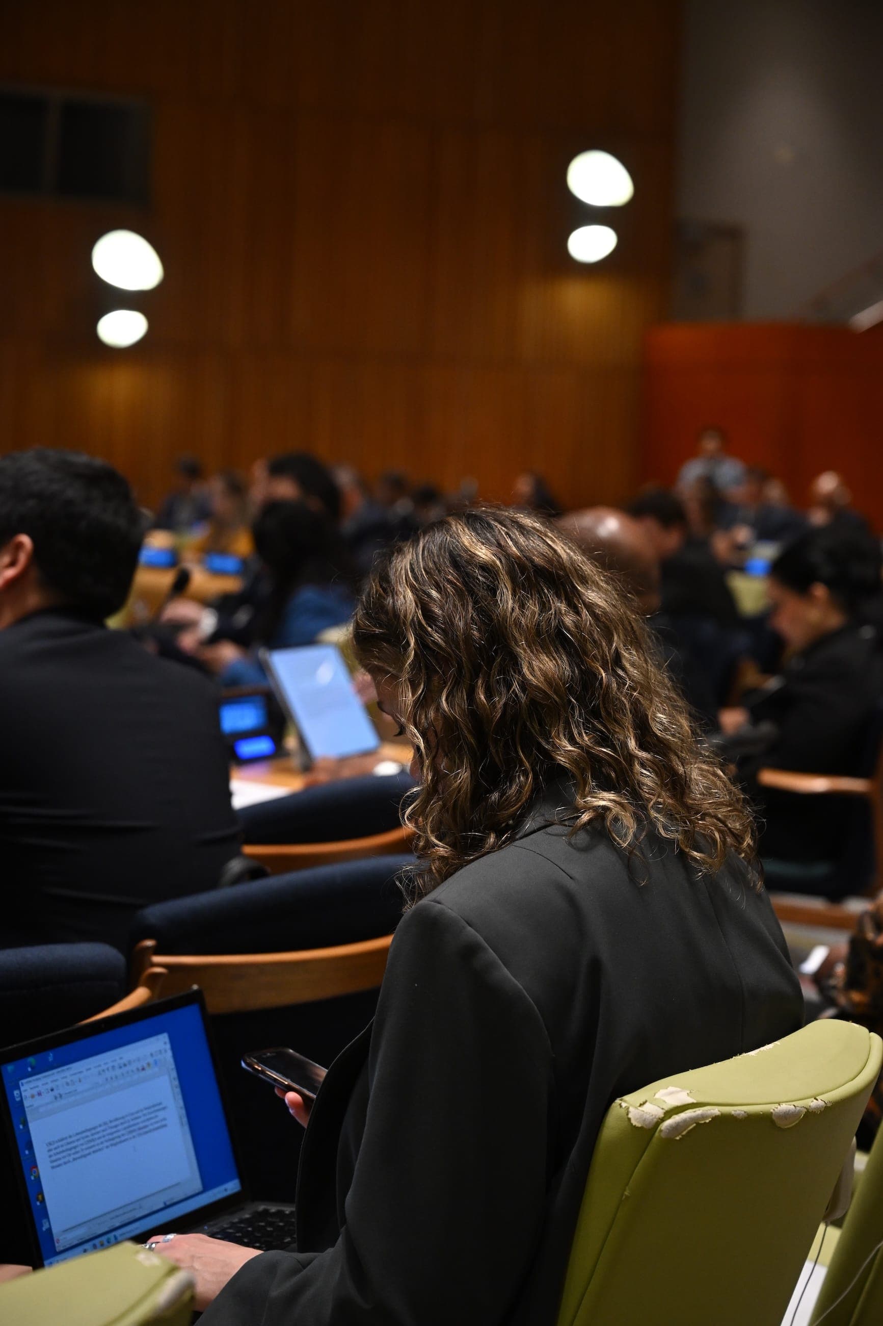 An attendee works on a laptop during a session in the General Assembly Hall.
