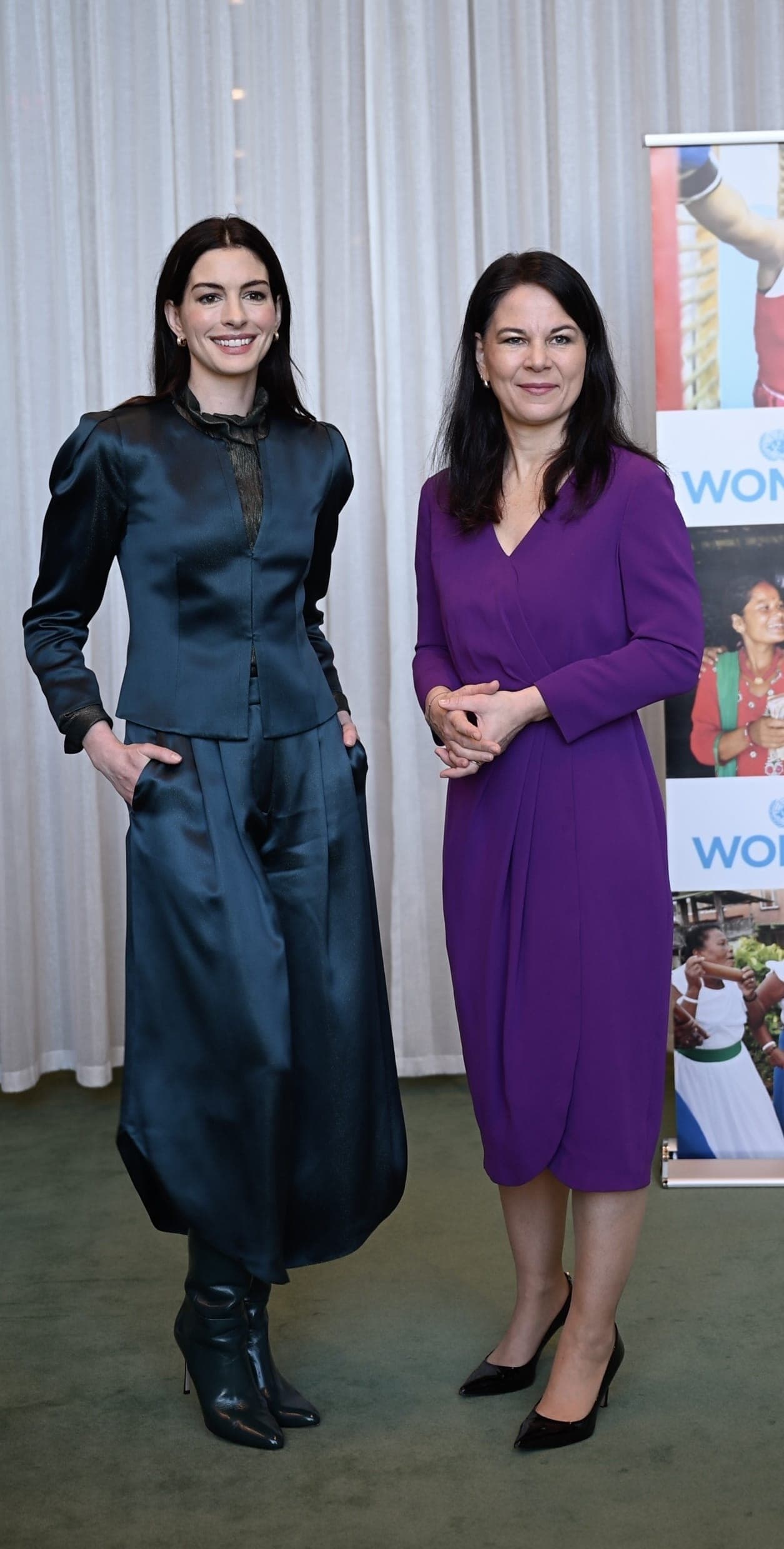 Two women pose together beside a United Nations Women banner.