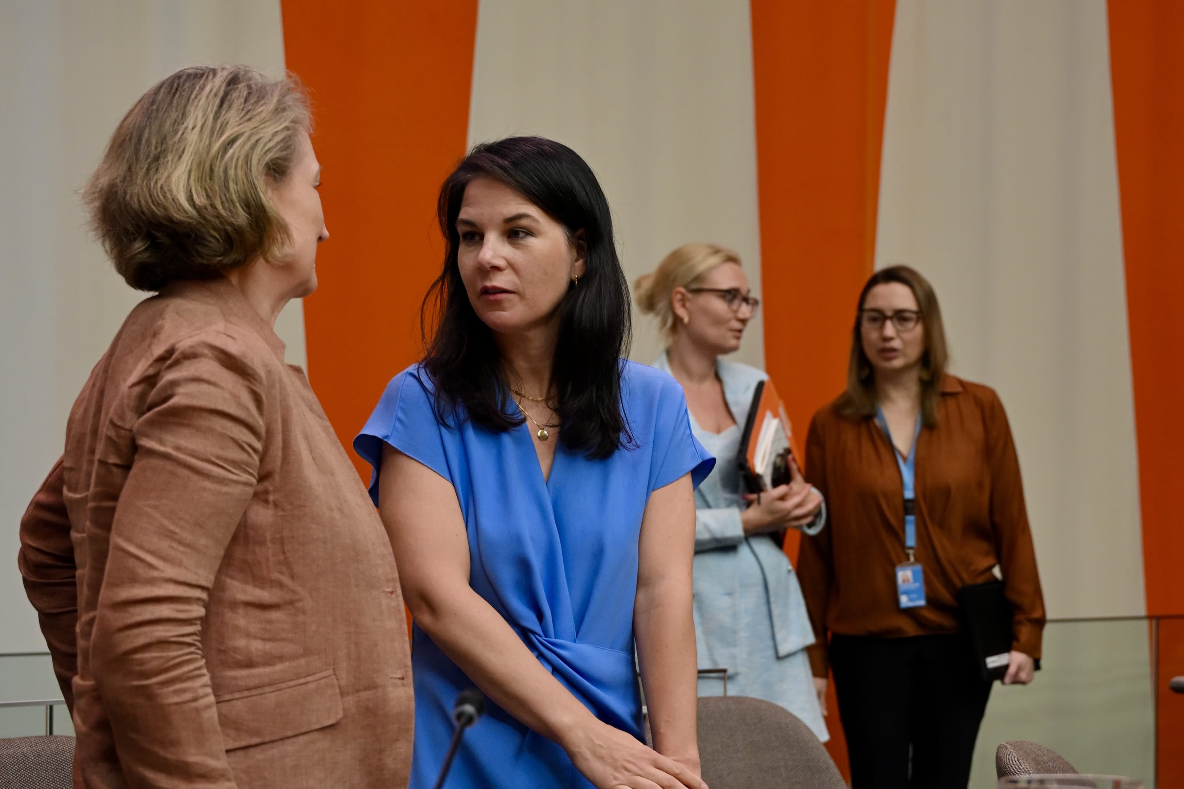 Four women converse in a meeting room with orange wall panels during a Pact for the Future event.