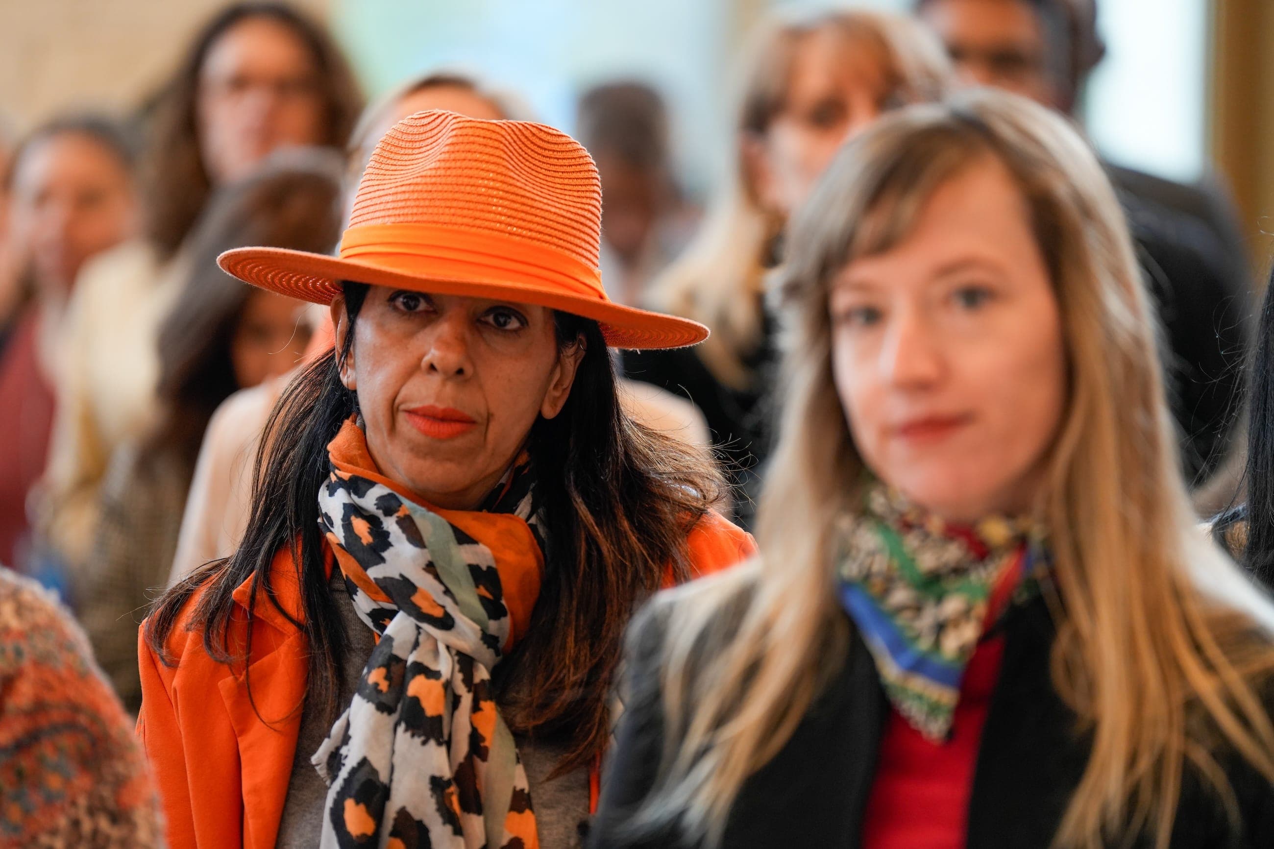 An audience member wearing an orange hat and scarf listens during the Orange the World event.