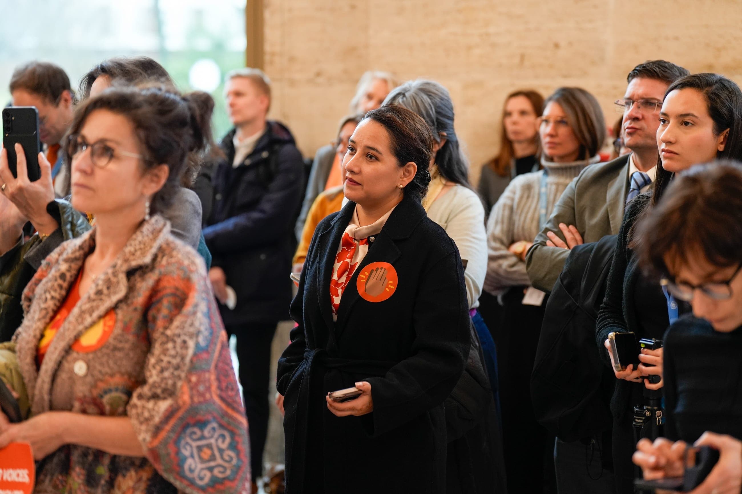 Event participants watch the programme, several wearing circular symbols from the Orange the World installation.