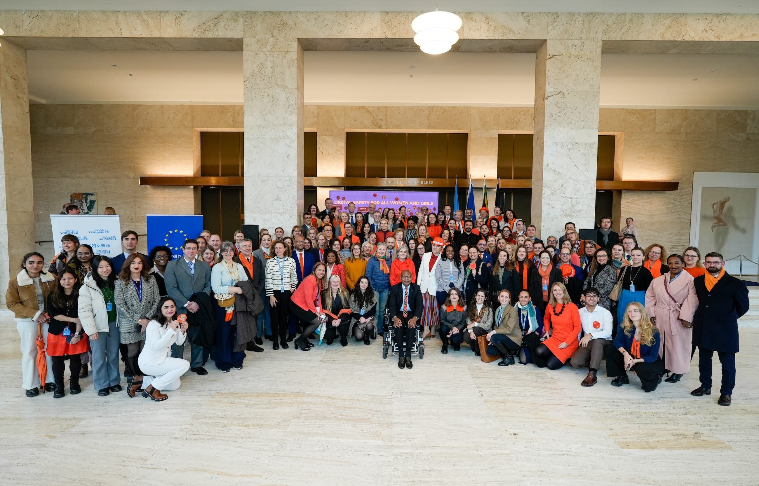 More than one hundred Orange the World event participants pose together in the United Nations assembly hall, many wearing orange.