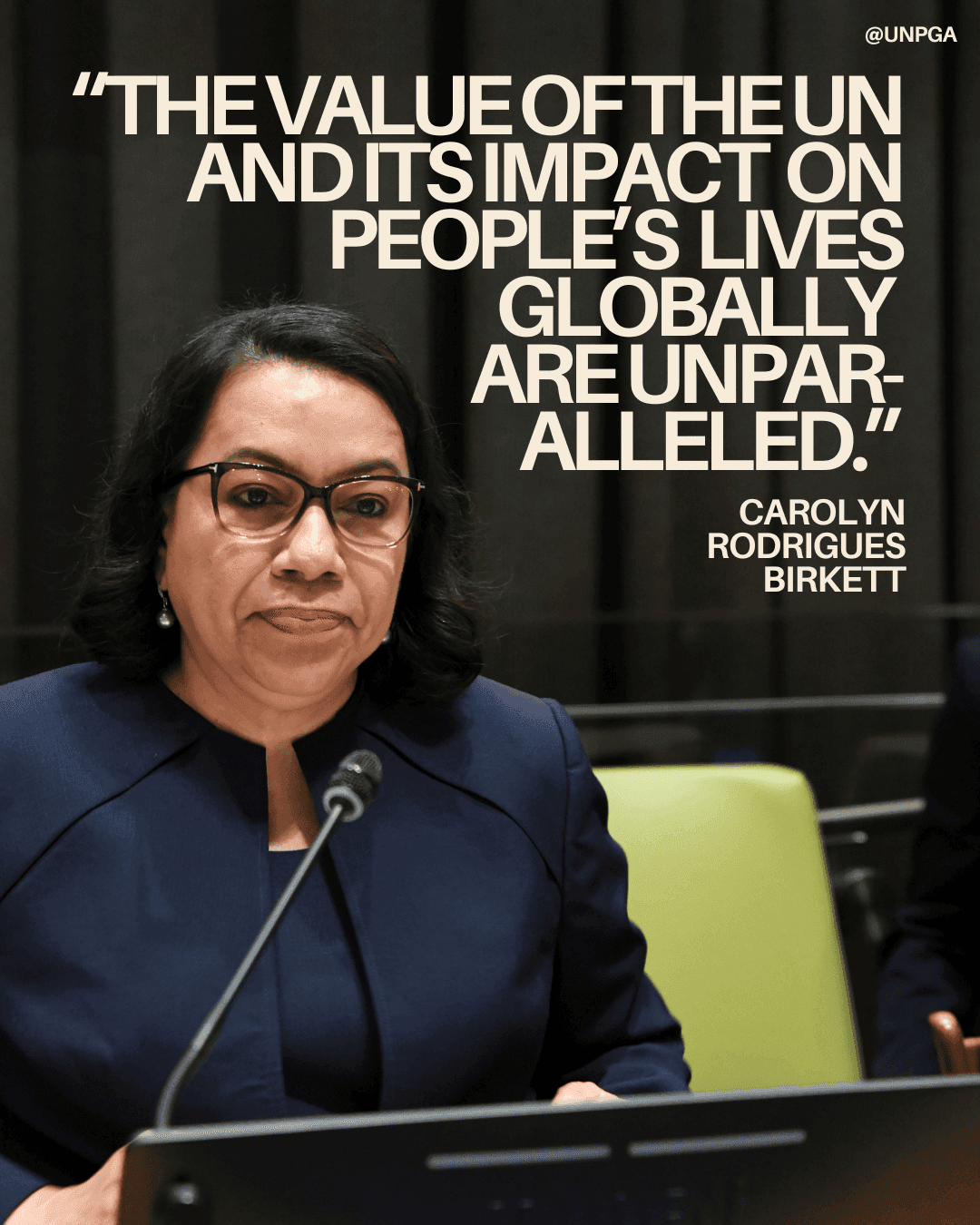 Carolyn Rodrigues Birkett at a microphone beside a quote about the United Nations’ impact on people’s lives.